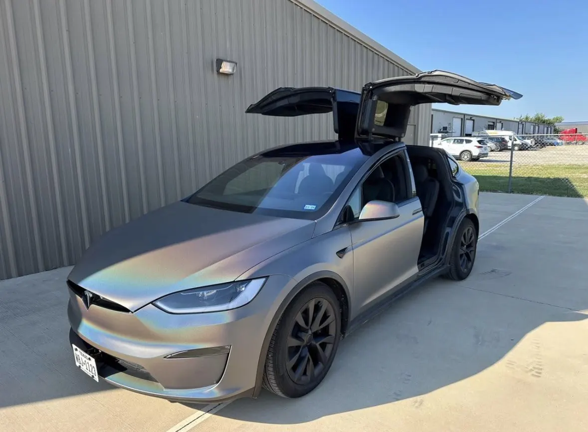 Tesla Model X with falcon-wing doors open outside the workshop